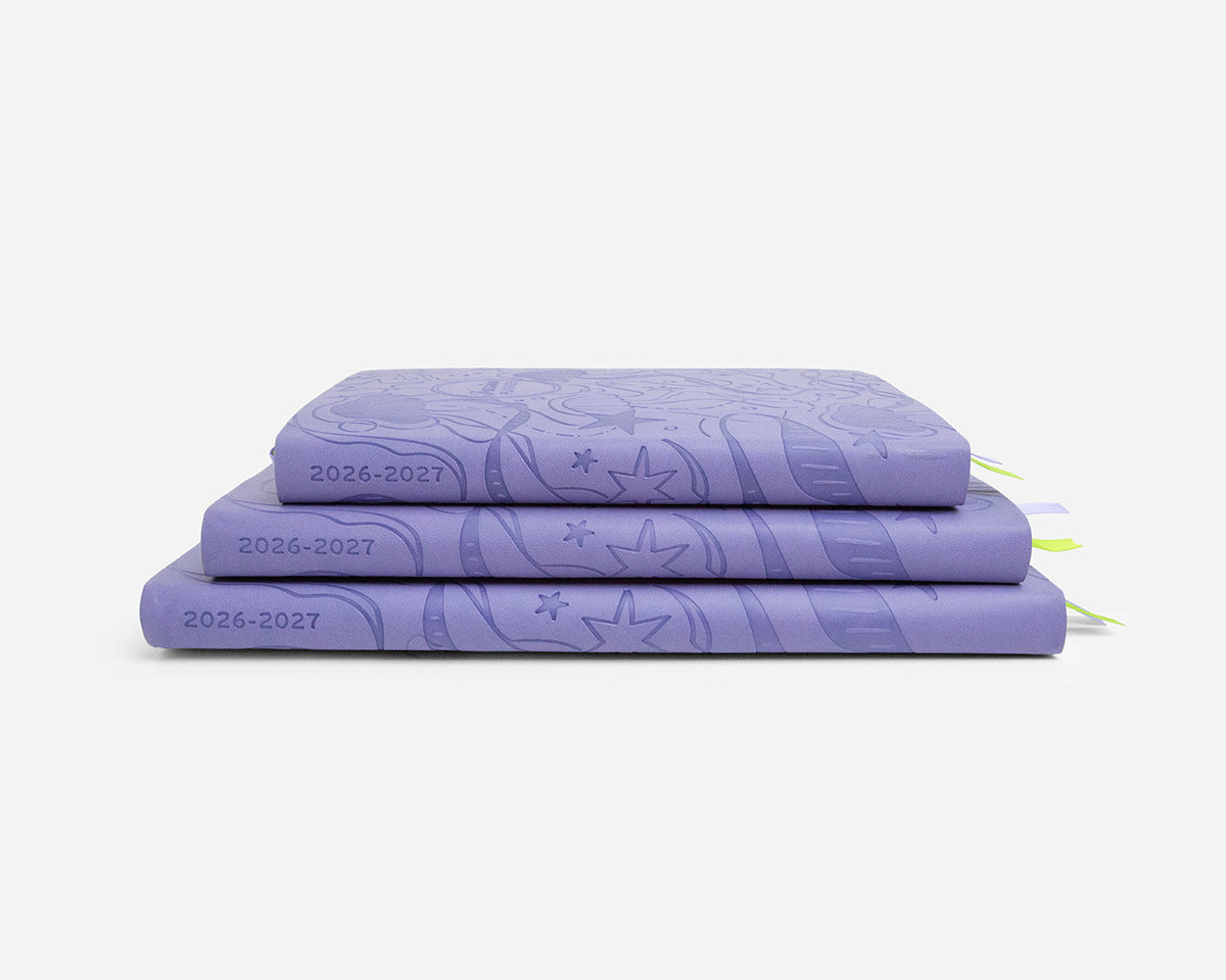 Three periwinkle planners with 2026-2027 on the spines stacked on a white background
