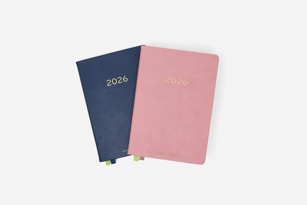 Two planners, one blue and one pink, with '2026' printed on them, on a white background.