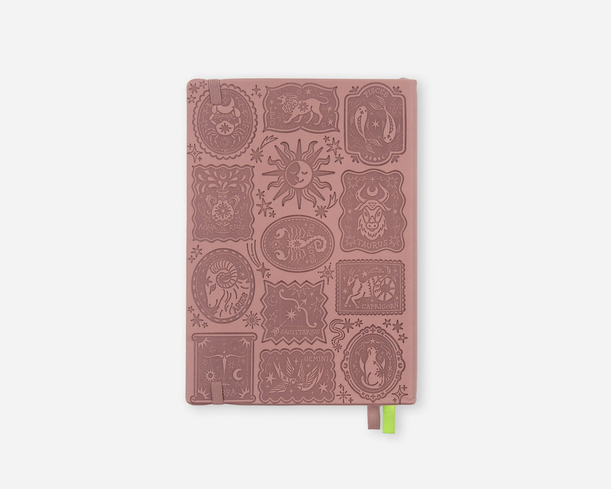A pink mauve 2027 planner with embossed zodiac animal and celestial motifs on the cover, featuring a small green ribbon bookmark at the bottom right, shown against a light gray background.