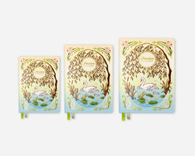 Three printed planners in a graduated size lineup, featuring an illustrated design of a weeping willow tree, swans, and a pond on the cover, with green ribbon bookmarks visible at the bottom.