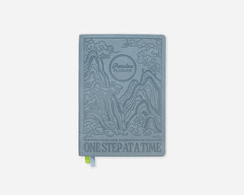 A light blue-gray 2027 planner titled 'ONE STEP AT A TIME' with embossed scenic illustrations and the 'Passion Planner' logo, shown on a clean white background.