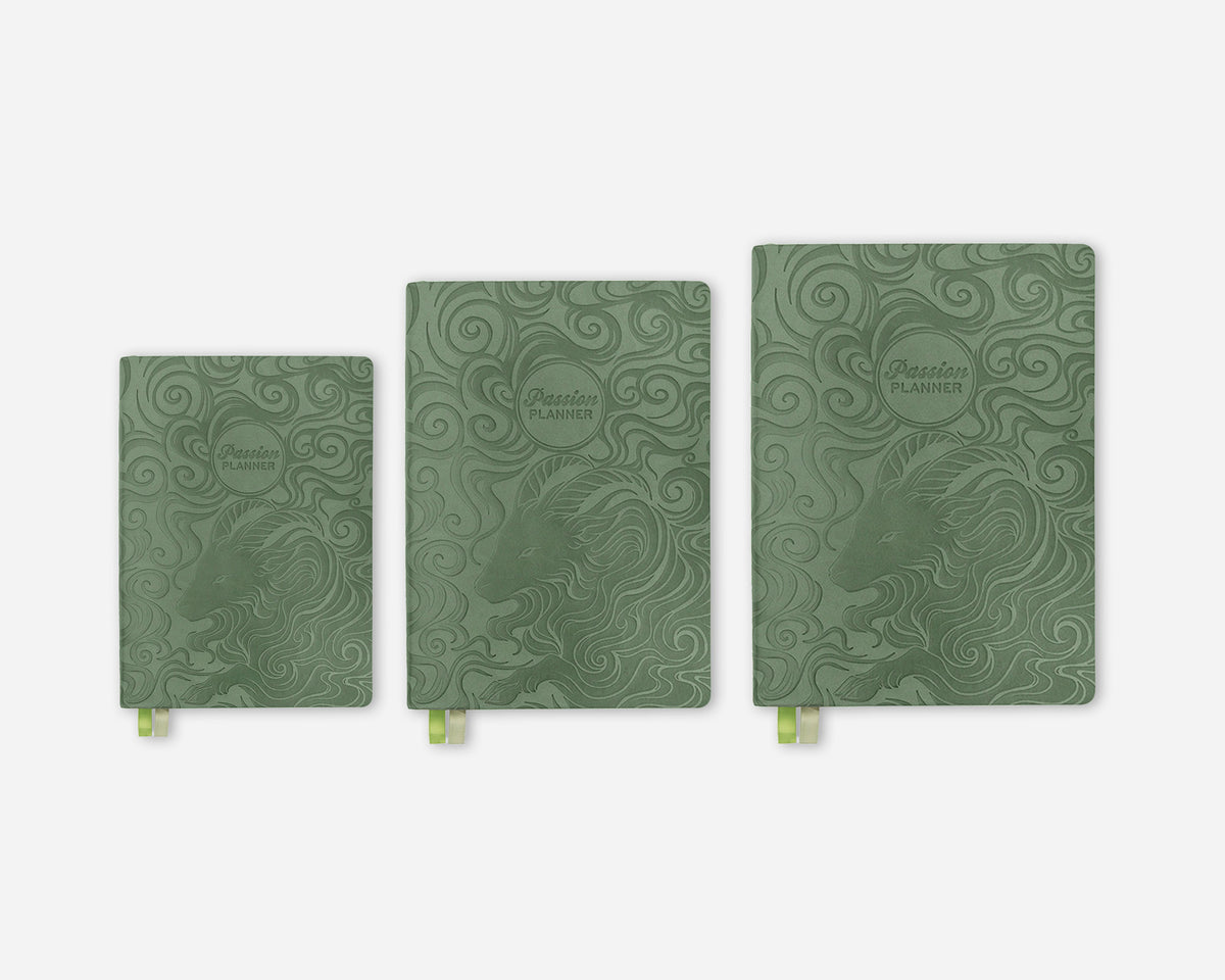 Three sage green 2027 planners in different sizes lined up horizontally on a light gray background. Each planner features an illustrated goat design and circular embossed logo that reads 'Passion Planner' and has a small green ribbon bookmark peeking out from the bottom.