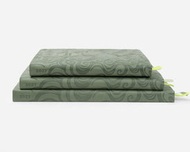 Three stacked sage green faux leather planners, each labeled '2027' on the spine, with small ribbon bookmarks peeking out on a clean white background.