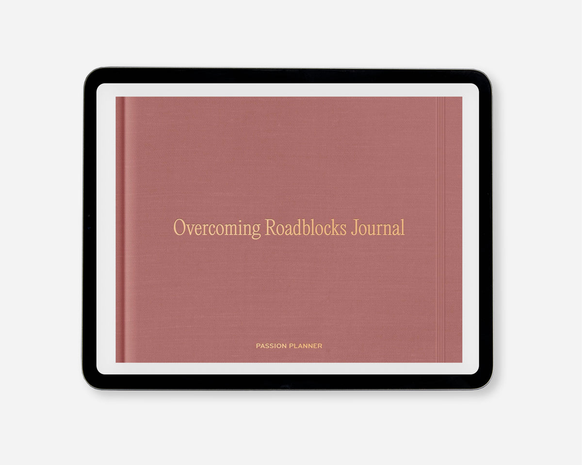 A digital journal titled 'Overcoming Roadblocks Journal' with a dusty rose cover and gold lettering, framed in a black tablet on a light gray background.