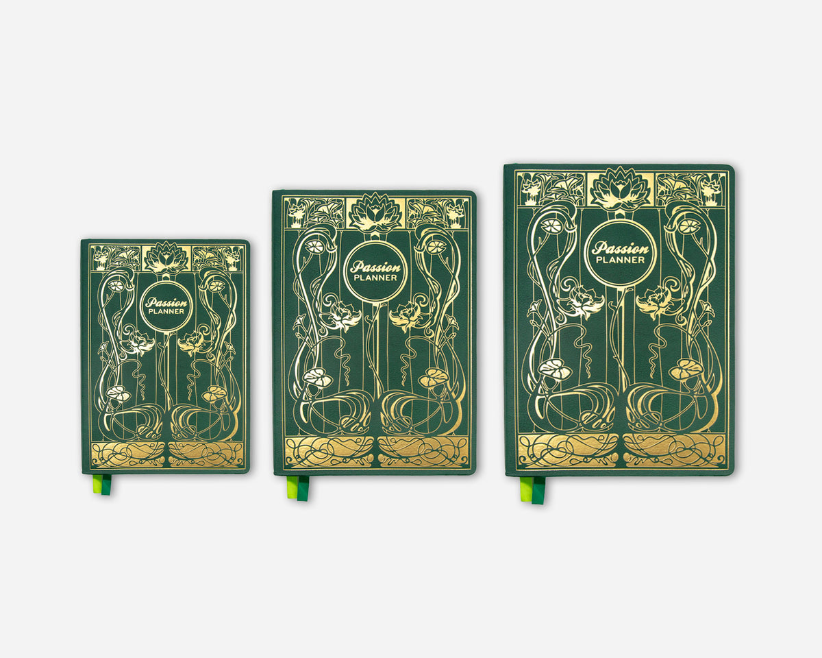 Three hardcover planners in a graduated size lineup, featuring an elegant Art Nouveau design in dark green with gold foil details and ribbon bookmarks.