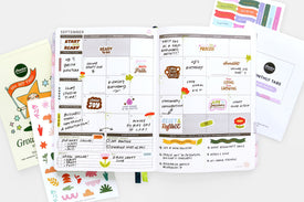 Planner with monthly tabs and stickers on a white surface