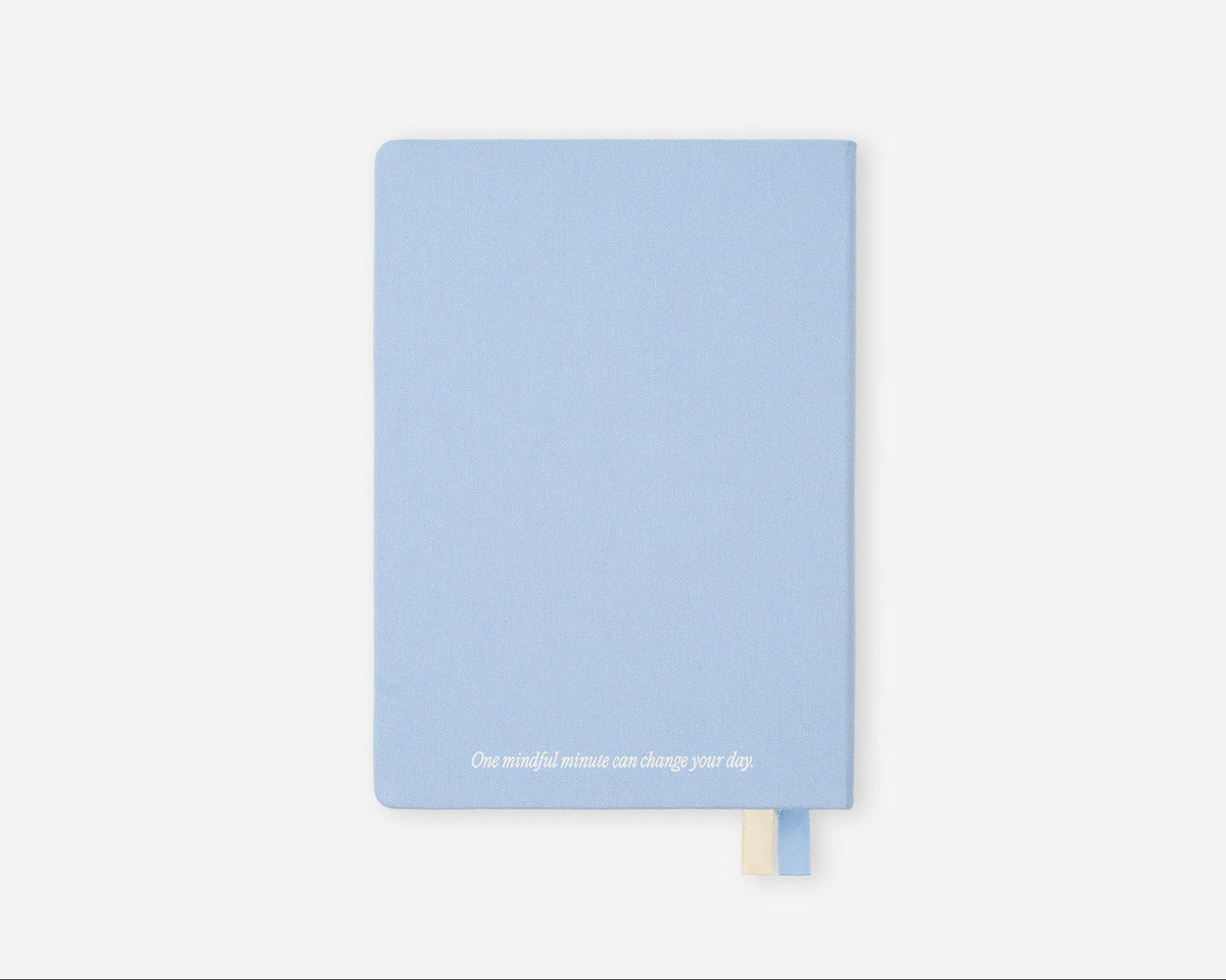 A light blue hardcover journal with a small white quote printed at the bottom and a matching light blue bookmark ribbon, shown on a clean white background.