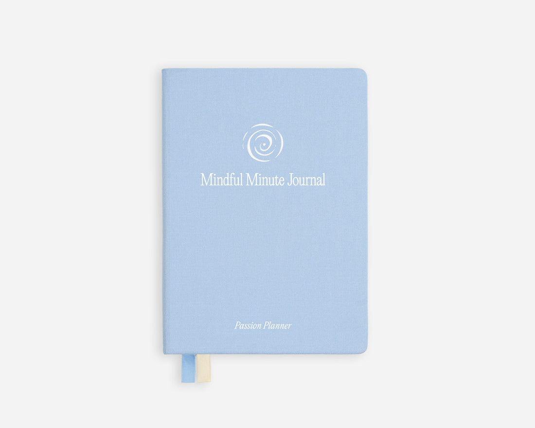 A light blue hardcover journal with a white spiral logo and the text &