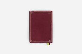 Maroon reading journal with decorative gold edges on a white background