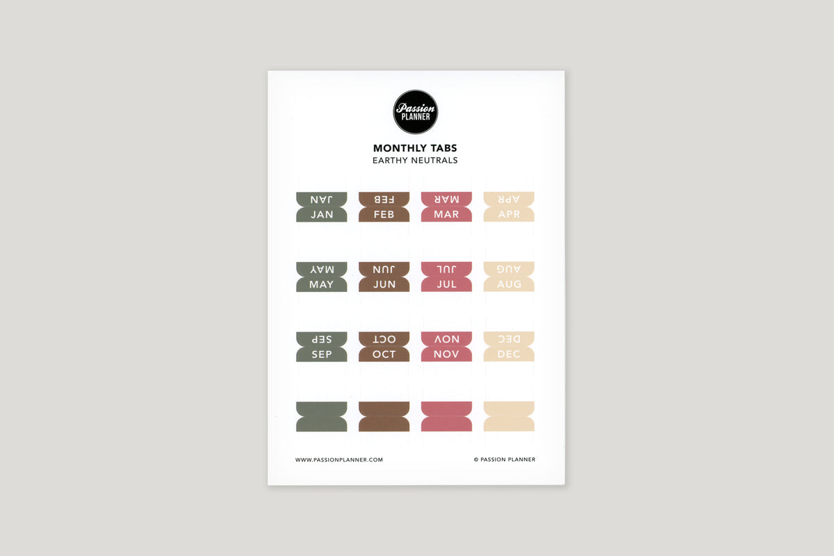 A sheet of multi-colored neutral monthly tabs labeled with different months of the year, designed to be used in a planner.