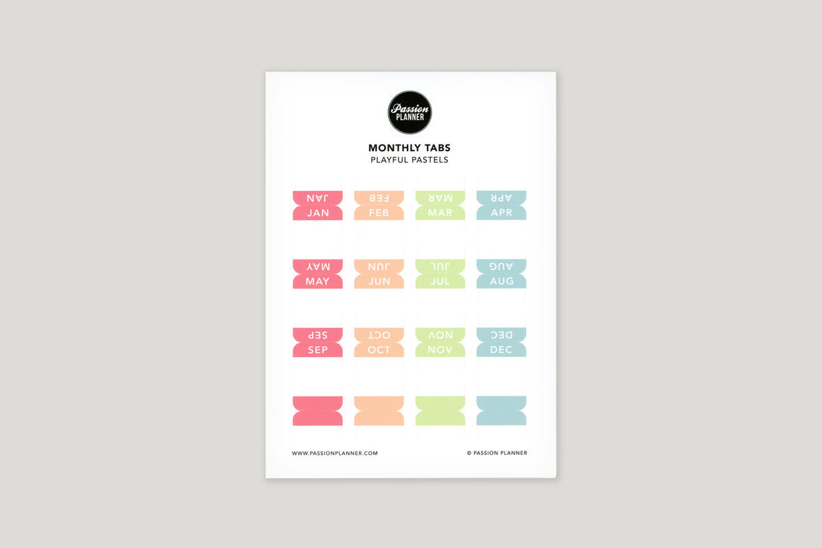 A sheet of multi-colored monthly tabs labeled with different months of the year, designed to be used in a planner.